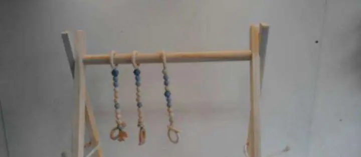 Photo from the official notice: Folding wooden activity gym with three hanging toys — choking & strangulation risk