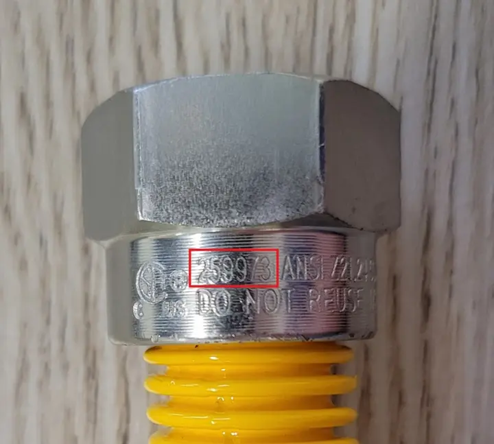 Close-up view of the flare nut on the recalled gas connector with CSA file number "259973" engraving